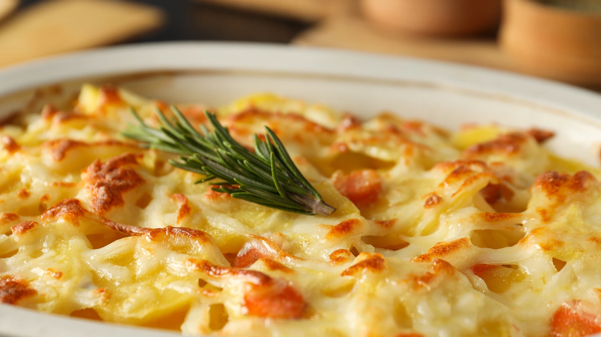 Close-up of a baked vegetarian casserole topped with melted cheese and garnished with a sprig of fresh rosemary, perfect for a comforting and hearty meatless meal.