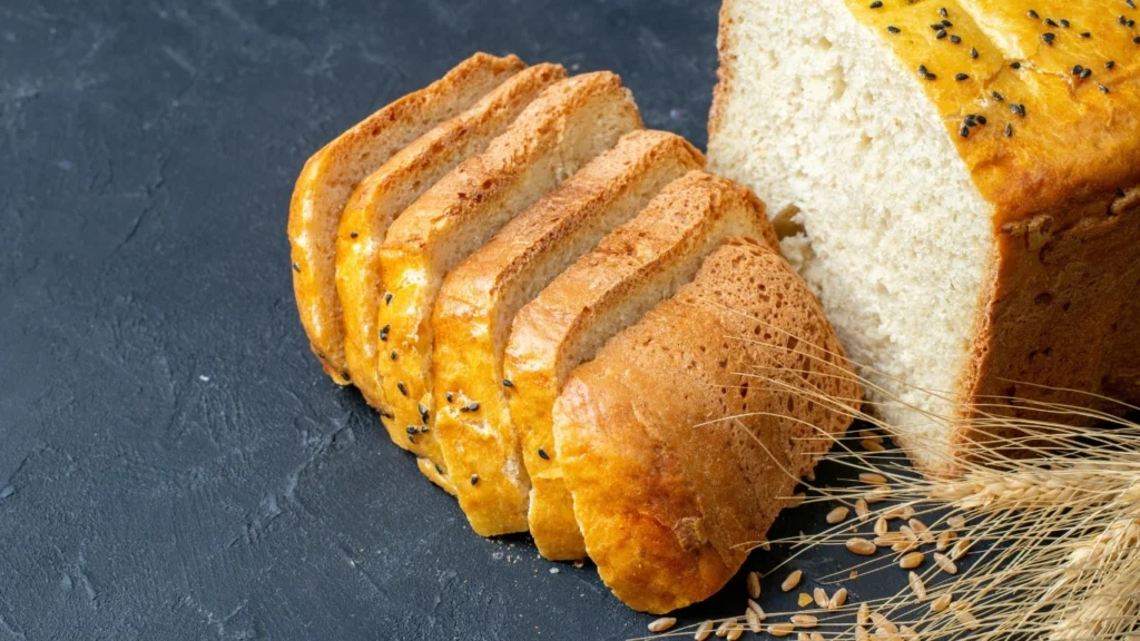 Freshly baked vegan banana bread slices with a golden crust and soft, fluffy texture, garnished with black sesame seeds, on a rustic background.