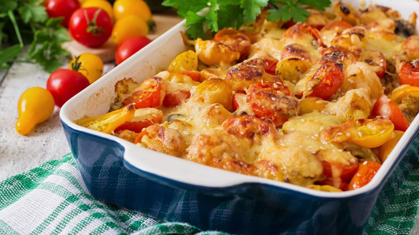 "Golden-topped vegan casserole surrounded by fresh vegetables and herbs on a rustic kitchen counter.