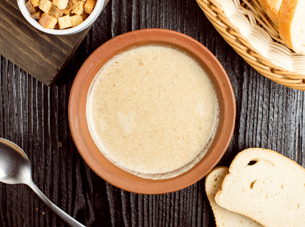 Rich and creamy 3 ingredient vegan gravy served in a pottery bowl with bread and crackers.