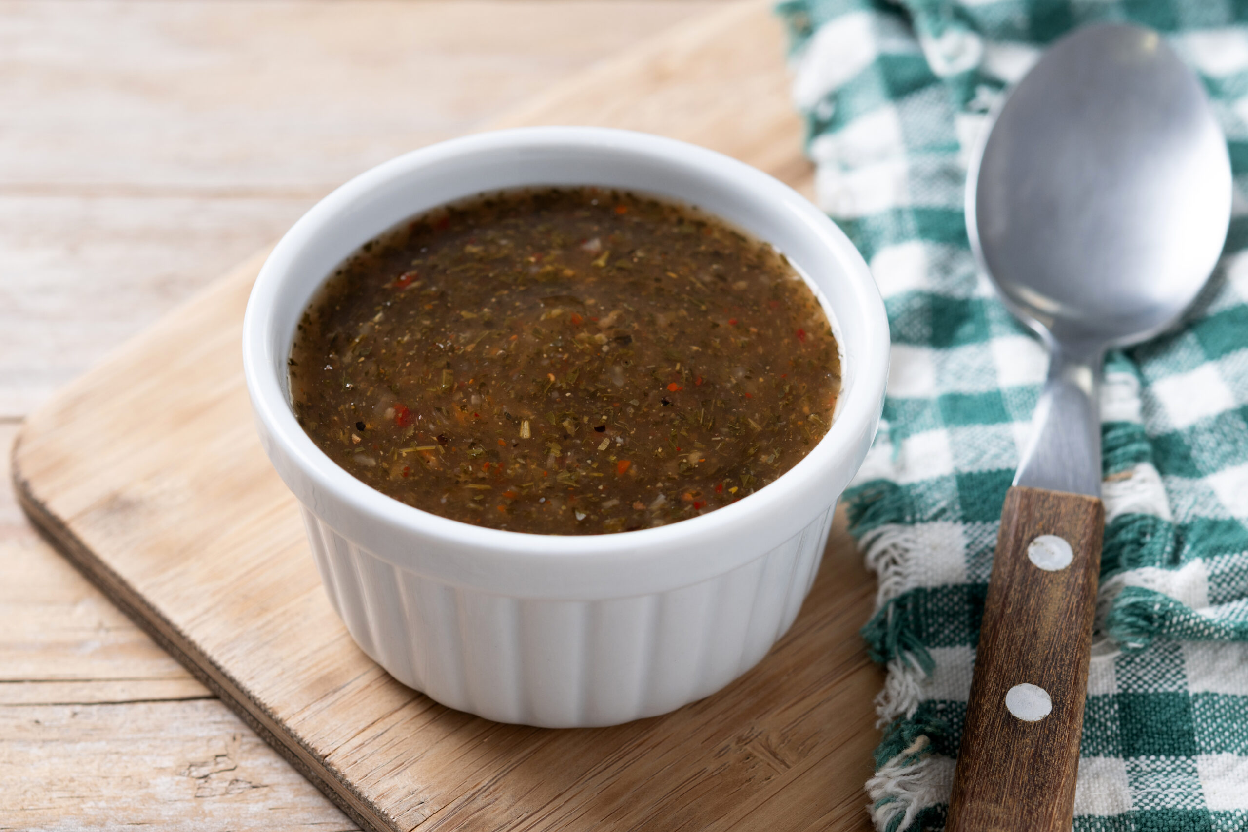 Homemade vegan brown gravy served in a white ramekin, featuring a rich texture and specks of herbs and spices, perfect for plant-based meals.