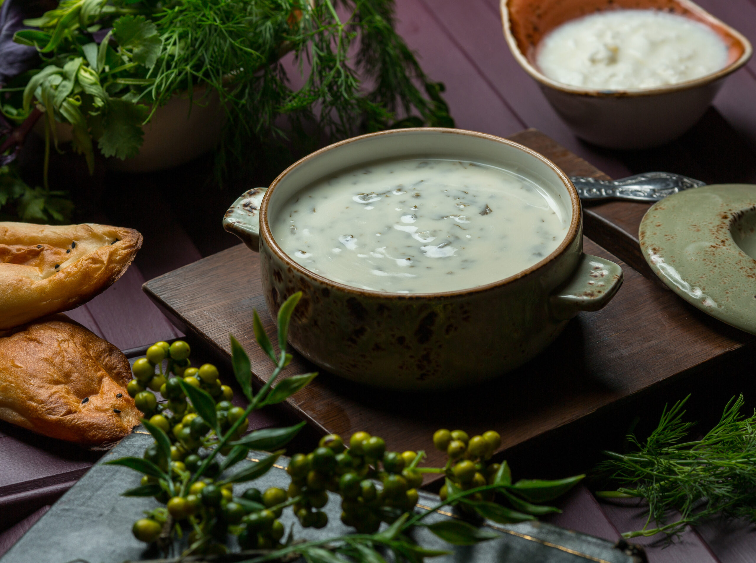 A bowl of vegan gravy garnished with herbs and served alongside bread, showcasing its smooth and flavorful texture.